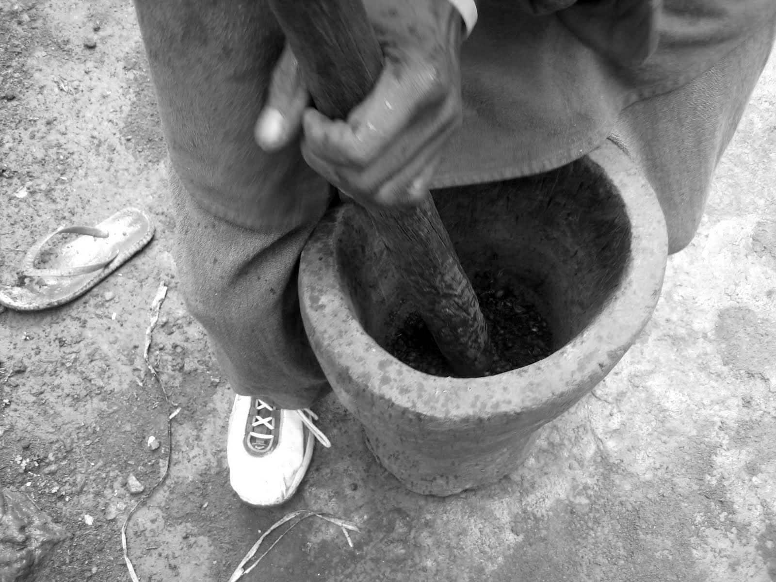 Small scale coffee farmer in Tanzania grinding coffee beans