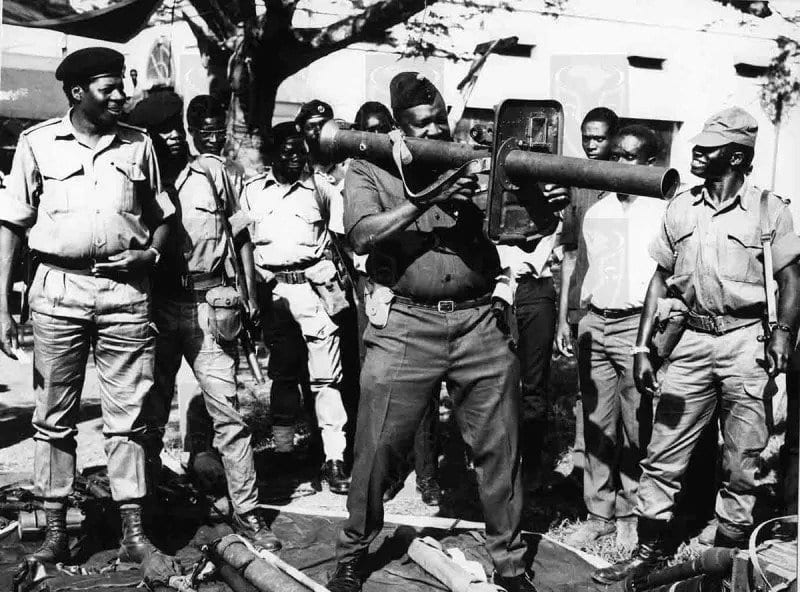 Idi Amin inspecting one of the bazookas while his military commanders are watching him