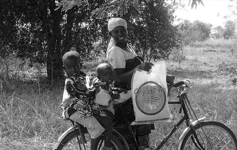 A Tanzanian village woman with her kids holding a Malaria net for prevention