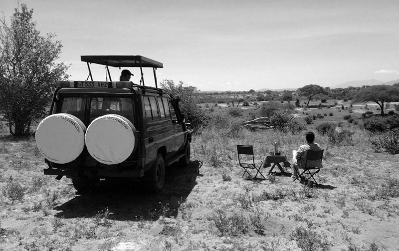 Tourists have set up a picnic to watch animals in Serengeti during their self drive safari Tanzania tour