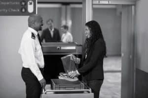 A Traveler interacting with airport security officer while collecting accessories