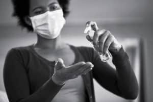 A woman wearing face mask while disinfecting her hands