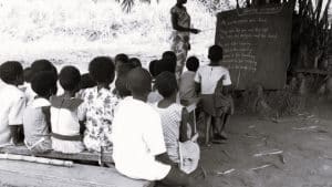 A teacher teaching children under a tree